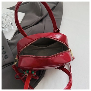 Top view of red patent leather handbag interior with smooth metal zipper and inner pocket