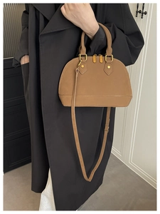 Close-up of brown textured leather shell bag with gold hardware and top handle