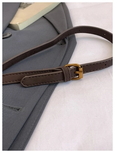 Detail of coffee brown leather strap with vintage gold buckle and fine stitching