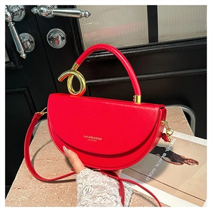 Detail of red semi-circular saddle bag featuring gold ring accent and round handle