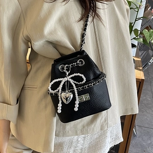 Chic black pebbled leather bucket bag with pearl bow, silver heart charm and chain strap