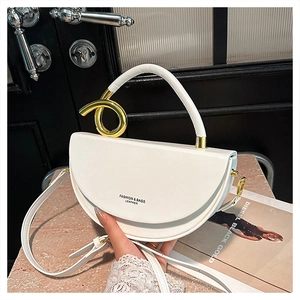 Detail view of white leather saddle bag with gold ring handle and fashion lettering