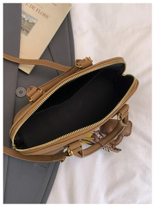 Detail view of khaki shell handbag showing spacious interior and metal zipper closure