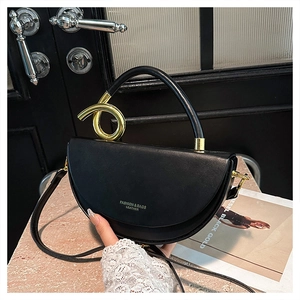 Detail of black saddle bag featuring unique gold spiral handle and fashion logo lettering