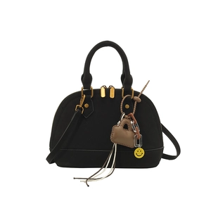 Detail view of black shell handbag showing dual zippers, handle and cute heart charms
