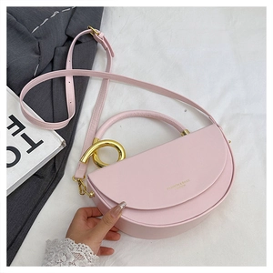 Detailed close-up of pink half-moon saddle bag with golden circular metal handle and strap