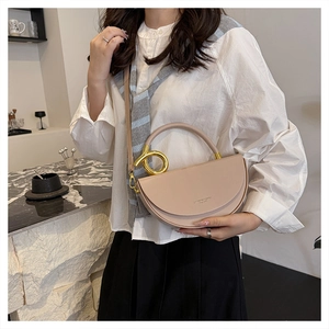 Detail of beige saddle bag featuring a unique gold metal ring handle and crossbody strap