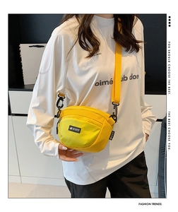 Détail du sac bandoulière en nylon jaune avec sangle noire réglable et poches zippées