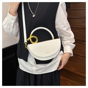 Detail of white leather saddle bag showing the gold metal ring handle and logo text