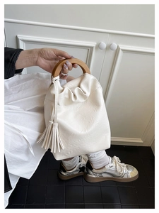 Detalle de bolso tipo cubo de cuero PU crema con asa de madera y borla suave