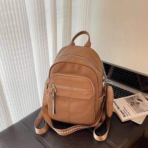 Caramel brown pebbled leather backpack with patterned straps and small coin purse attached