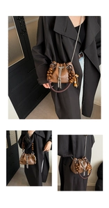 Detail of vintage brown bucket bag with beaded handle and metallic tassel accents