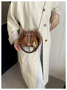 Detail of brown PU leather bucket bag featuring wood bead handle and silver metal tassels