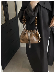 Detail of vintage brown bucket bag with wooden bead handle and silver metal fringe