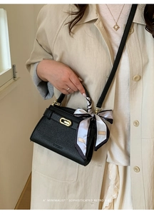 Détail du sac Kelly en cuir grainé noir avec poignée en soie et fermoir doré