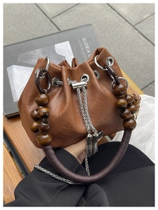 Detail of caramel PU bucket bag with retro wooden beads and silver drawstring chain