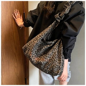 Detail of the orange embroidered Poermalis logo on the leopard print canvas shoulder bag