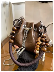 Detail of vintage brown leather bucket bag with wooden bead handle and tassel charms