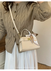 Détail du sac bandoulière crème avec fermoir doré et foulard en soie décoratif