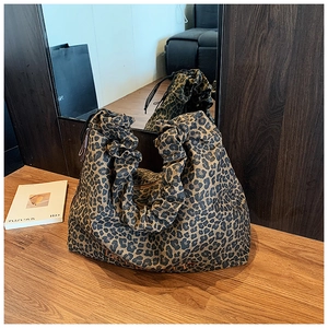 Detailed view of leopard print tote bag with ruched handle and embroidered brand text