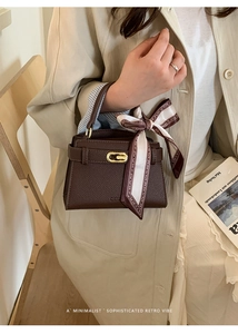 Détail d'un sac à main en cuir marron foncé avec boucle dorée et foulard en soie