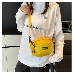Détail d'un sac bandoulière en nylon jaune vif sur mannequin avec sangle et poche zippée