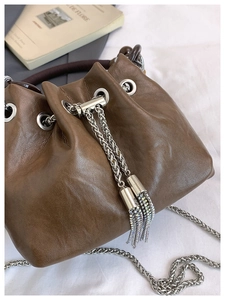 Detail of brown leather bucket bag featuring crystal tassels and silver chain strap
