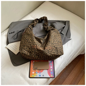 Close-up of leopard print shoulder bag with orange embroidery and ruffled strap details