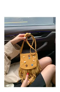 Detail view of yellow suede bag with fringe, colorful buttons and white shell charm detail