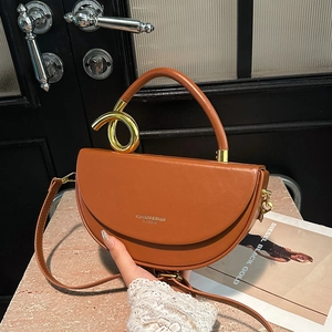 Brown leather saddle crossbody bag with unique gold spiral handle and embossed logo