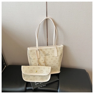 Detail view of cream tote bag with cartoon bow patterns and matching small pouch