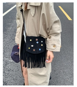 Detail of vintage black suede crossbody bag with bohemian tassels and colorful button studs