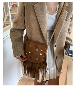 Close-up of bohemian brown suede crossbody bag featuring colorful flower charms and fringe