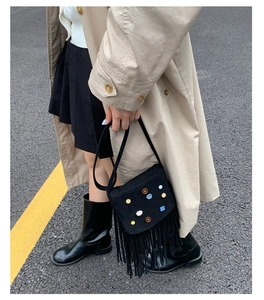 Detail of bohemian black suede bag with colorful flower appliques and long fringe trim