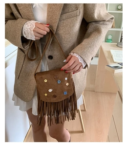 Close-up of vintage brown suede crossbody bag featuring tassels and colorful buttons