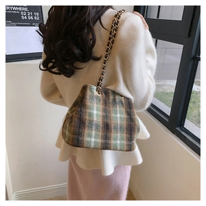 Detail of vintage plaid fabric texture and gold chain strap on a green wool shoulder bag
