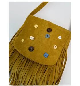 Detail of bohemian mustard yellow crossbody bag with vintage tassels and shell decorations