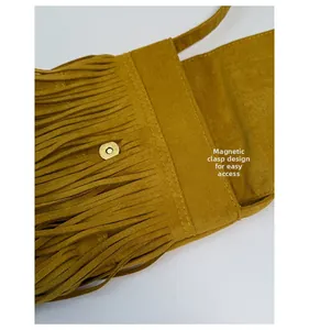 Detail of yellow suede bag featuring fringe trim and a gold round magnetic snap closure
