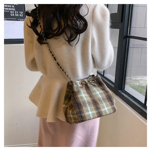 Détail d'un sac seau vintage en tweed à carreaux avec bandoulière chaîne tressée