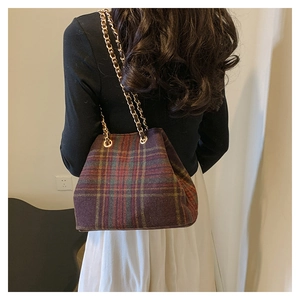 Close-up of vintage tartan bucket bag with wool texture and golden chain straps