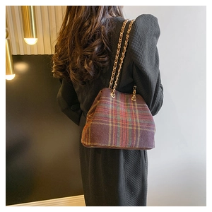 Detail of vintage purple plaid wool bucket bag with gold metal chain strap on model