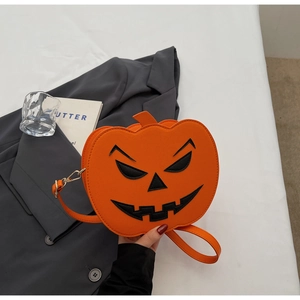 Détail du sac citrouille orange avec visage noir porté par une femme en tailleur