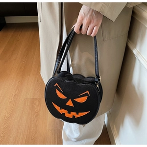 Détail d'un sac à bandoulière noir en forme de citrouille avec visage orange et boucle en métal