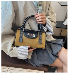 Détail du sac Boston en daim avec breloque cœur et poignées en cuir noir