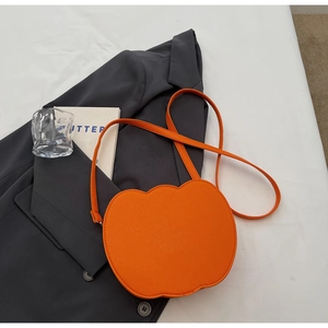 Détail d'un sac bandoulière orange en forme de pomme en similicuir sur blazer gris