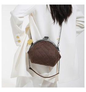 Macro view of brown quilted suede kiss-lock bag with metallic chain and gold pendant