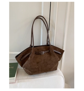 Detail view of deep brown suede tote bag with slim buckle and cylindrical handles