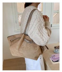Detail of the suede texture and elegant metal buckle on the large beige tote bag