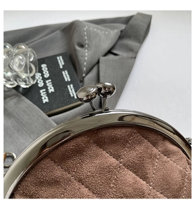 Detailed macro view of retro brown quilted suede handbag with silver metal kiss lock closure