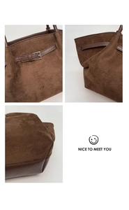 Detail view of dark brown suede tote bag with metal buckle and stitched leather bottom